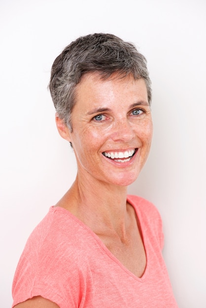 Close up beautiful middle age woman smiling by white wall