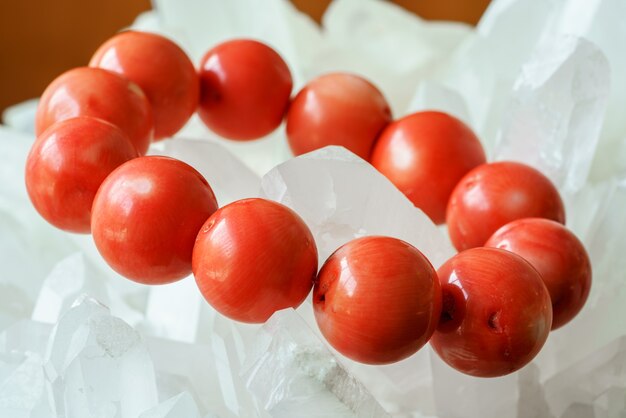 Foto primo piano di bellissime perle di corallo rosso rotonde preziose su sfondo di quarzo