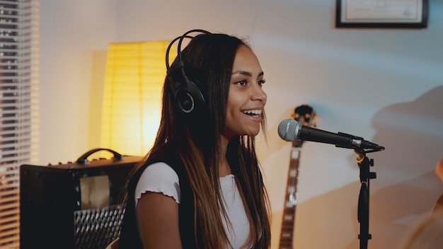 Close-up of beautiful smiling girl in headphone singing her favourite song on the rehearsal