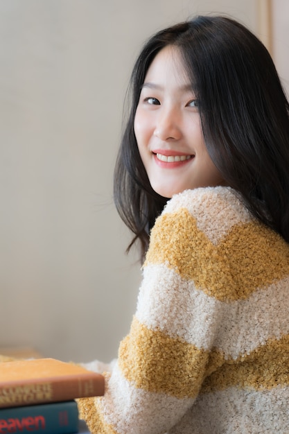 Close up of beautiful student wearing yellow sweater and smiling while reading books