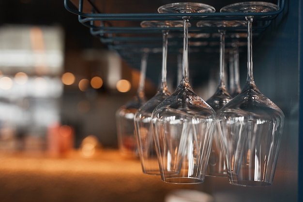 Primo piano di bei bicchieri da vino appesi a testa in giù su stendibiancheria in vetro in un bar o in un pub