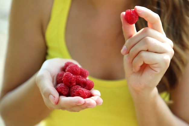 Close up of beautiful woman eating raspberries outdoor