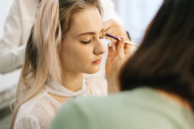 Close-up of beautiful woman model preparing for filming in lighting dressing room. Concept of backstage work.