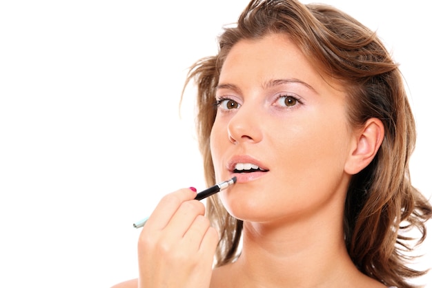 A close-up of a beautiful woman putting on makeup over white background