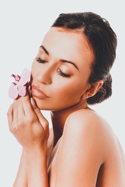 Foto close-up di una bella donna con un fiore sullo sfondo bianco