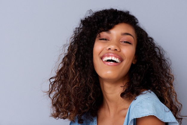 Close up beautiful young black woman laughing against gray backgorund