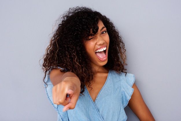 Close up beautiful young black woman winking and pointing finger