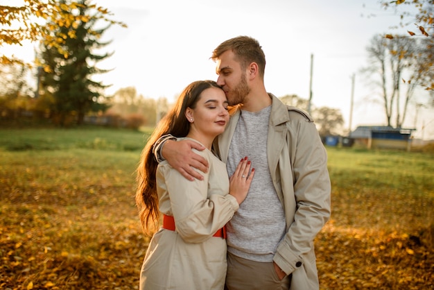Close up of a beautiful young happy couple in love embracing while spending time in the autumn park