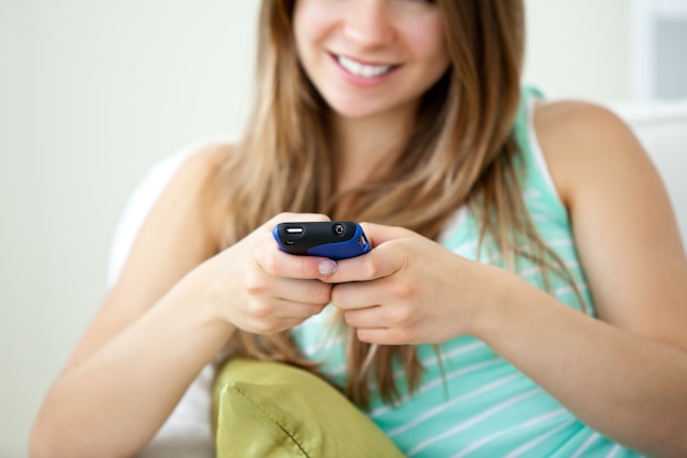 Крупный план красивая молодая женщина, texting с ее сотовый телефон на диване