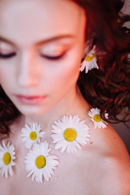 Foto close-up di una bella giovane donna che indossa fiori e trucco