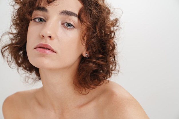Close up beauty portrait of an attractive young topless woman with short curly brown hair 