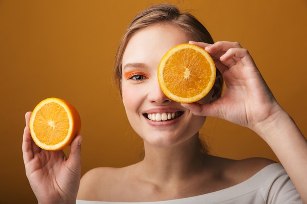 Close up beauty portrait of a beautiful sensual young woman isolated, showing sliced orange