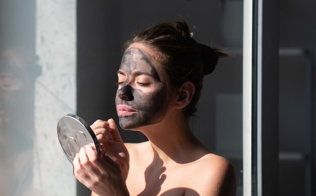 Close up beauty portrait of a beautiful woman with facial mud mask mask for skin lifting and antiagi