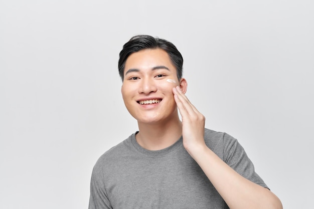 얼굴 크림을 바르는 반 벌거벗은 만족한 청년의 아름다움 초상화를 클로즈업