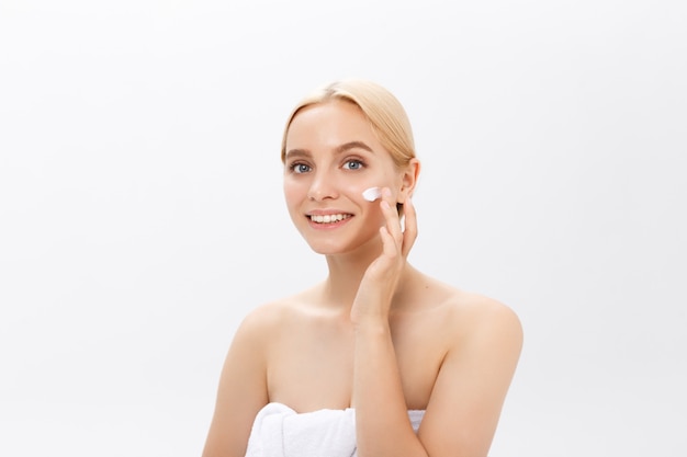 Close up beauty portrait of a laughing beautiful half naked woman applying face cream 