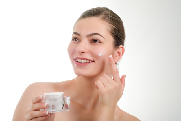 Close up beauty portrait of a laughing beautiful woman applying face cream and staring isolated