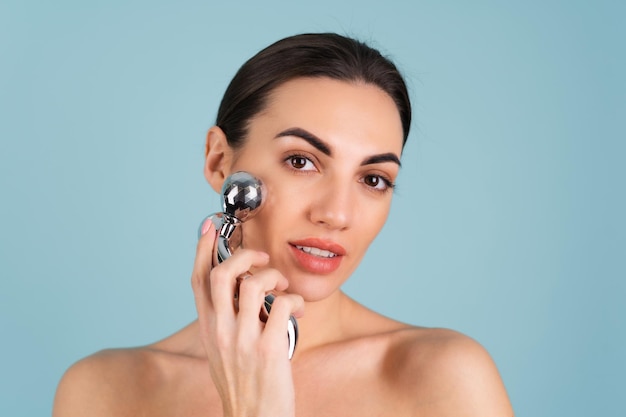 Close up beauty portrait of a woman with perfect skin and natural make-up, plump nude lips, holding a roller massager for face and neck