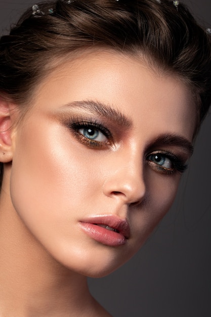 Close up beauty portrait of young woman with beautiful bronze smokey eyes makeup
