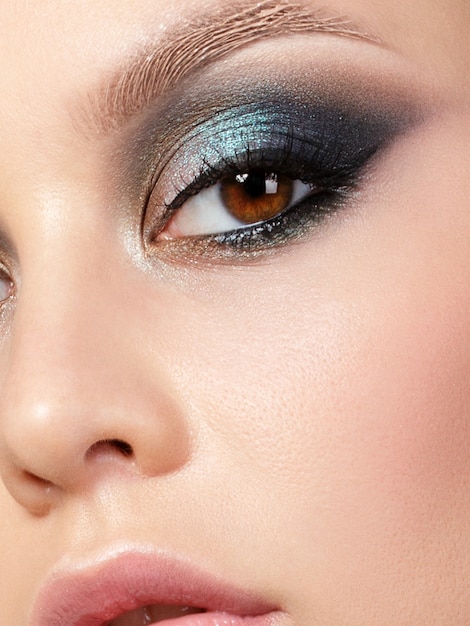 Close up beauty portrait of young woman with beautiful fashion makeup. Modern fashion makeup. Colorful smokey eyes. Extreme closeup, partial face view