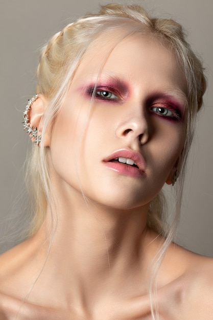 Close up beauty portrait of young woman with coral red smokey eyes. Perfect skin and fashion make up. Sensuality, passion, trendy youth makeup concept.