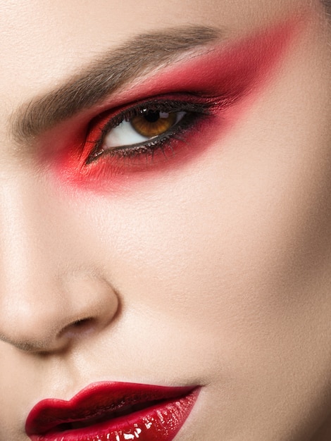 Close up beauty portrait of young woman with red smokey eyes