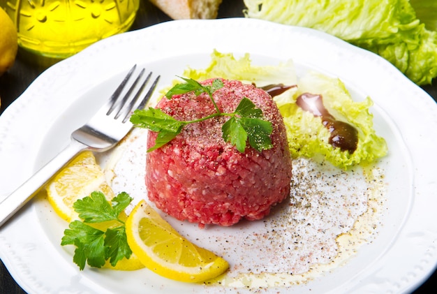 Close up of beef tartar with fresh salad and lemon slice