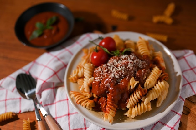 Close-up beeld Fusilli pasta met zelfgemaakte tomatensaus in een witte plaat met bestek op tafel