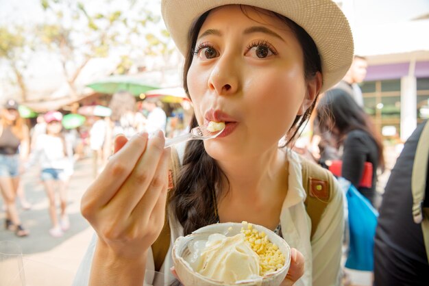 close-up beeld portret van vrouwelijke reiziger die eet en geniet van populair kokosijs op de Thailand-reisvakantie in de beroemde Chatuchak-weekendmarktstraat.