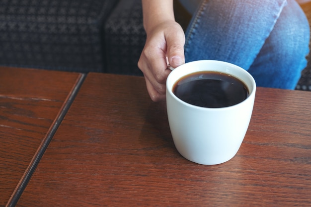 Close-up beeld van de hand van een vrouw met een kop warme koffie te drinken zittend in café