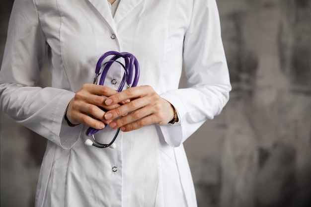 Close-up beeld van een arts met een stethoscoop in haar handen tegen de achtergrond van een wazig ziekenhuis