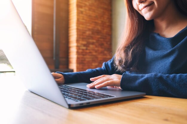 Close-up beeld van een Aziatische vrouw die werkt en typt op een laptopcomputer op houten tafel