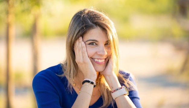 Foto close-up beeld van een gelukkige vrouw die naar de camera kijkt en glimlacht terwijl ze van het buitenleven geniet