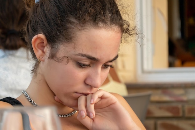 Close-up beeld van een jonge vrouw die naar beneden kijkt met een bedachtzame uitdrukking op haar gezicht