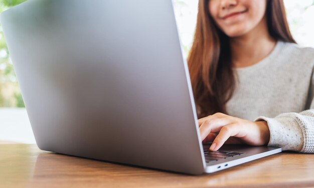 Close-up beeld van een jonge vrouw die werkt en typt op het toetsenbord van de laptop op houten tafel