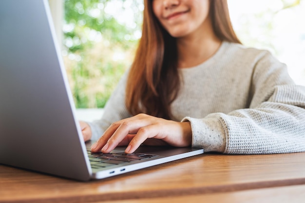 Close-up beeld van een jonge vrouw die werkt en typt op het toetsenbord van de laptop op houten tafel