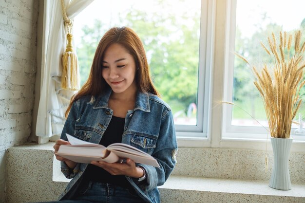 Close-up beeld van een mooie Aziatische vrouw die thuis een boek zit te lezen