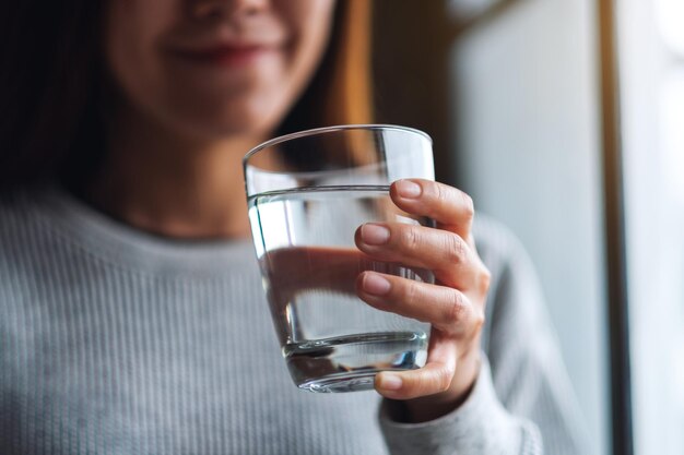 Foto close-up beeld van een mooie jonge aziatische vrouw met een glas water om te drinken