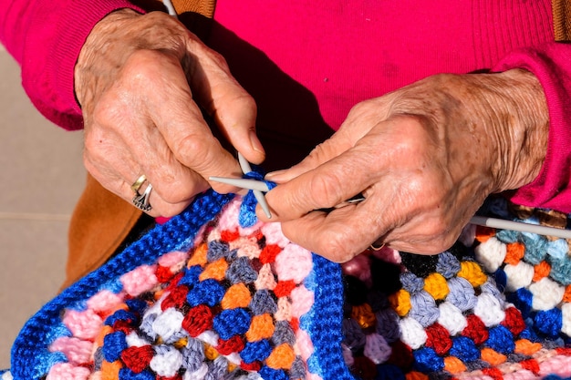 Close-up beeld van een oude vrouw met breinaalden en wol