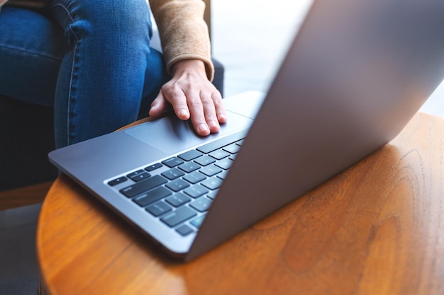 Close-up beeld van een vrouw die werkt en aanraakt op laptop touchpad op houten tafel