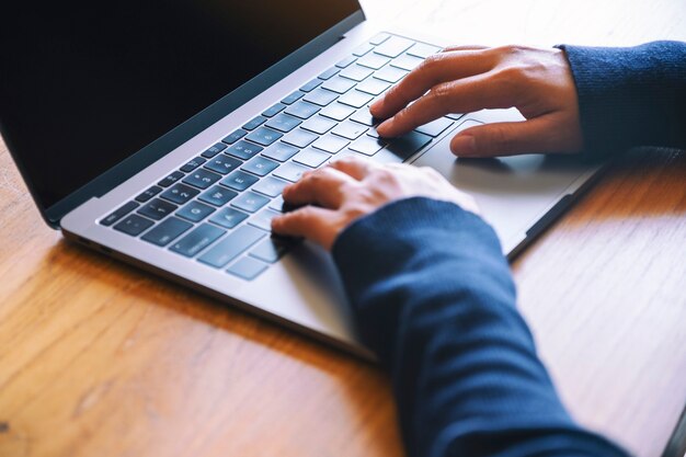 Close-up beeld van een vrouw die werkt en typt op een laptopcomputer op houten tafel