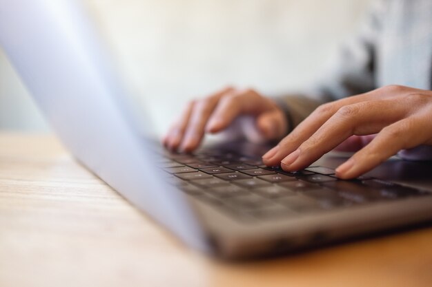 Close-up beeld van een vrouw die werkt en typt op het toetsenbord van de laptop op de tafel