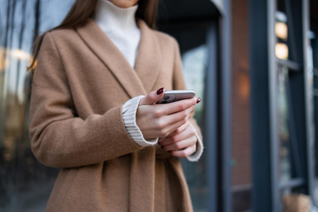 Close-up beeld van een vrouw in een jas met een smartphone in haar handen