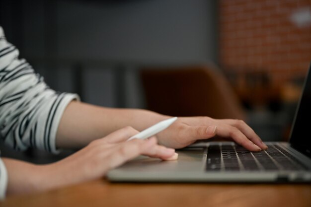 Close-up beeld van een vrouwelijke freelancer met behulp van haar laptop in een coffeeshop