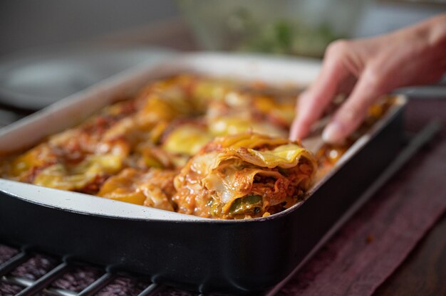 Close-up beeld van heerlijke vers gebakken hete romige veganistische lasagne in een kookpan