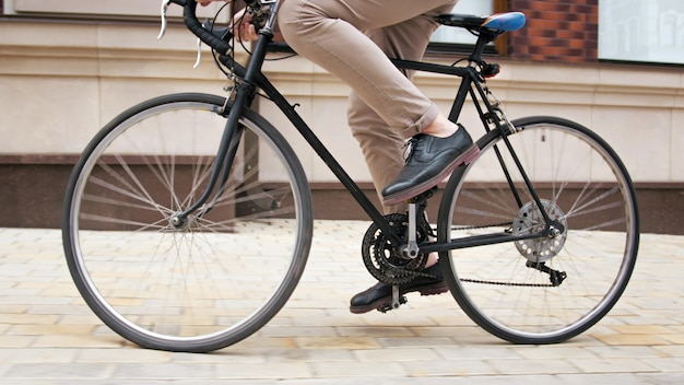Close-up beeld van jonge man rijden op vintage fiets op straat in de stad.