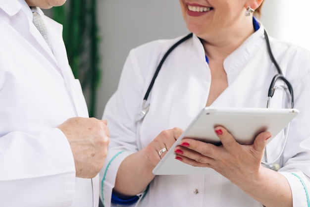 Close-up beeld van man en vrouw artsen die tablet gebruiken tijdens de werkdag in de kliniek.