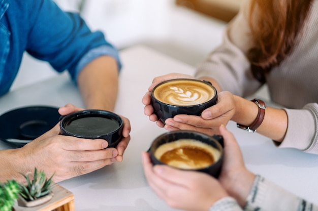 Close-up beeld van mensen die koffie vasthouden en ervan genoten om koffie te drinken op tafel in café