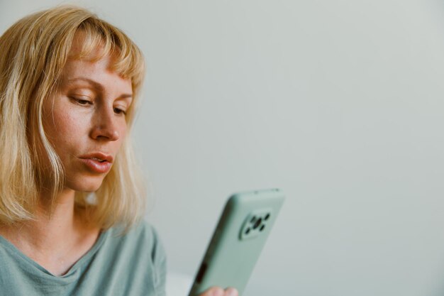 Close-up beeld van mooie vrouw zittend op een gezellig interieur en het gebruik van moderne smartphone apparaat vrouwelijke handen typen SMS-bericht via mobiele telefoon social networking concept