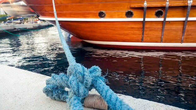 Close-up beeld van oude houten schip afgemeerd in zeehaven met blauw touw.