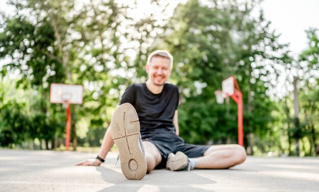 Close-up beeld van schoenzool van sportieve man man zit in het stadion buiten. Atleet mannelijke persoon tijdens training buitenshuis